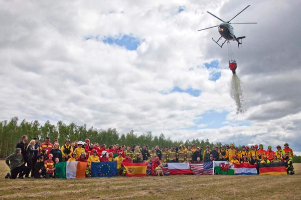 internationale Waldbrandexperten stehen unter fliegendem Löschhubschrauber